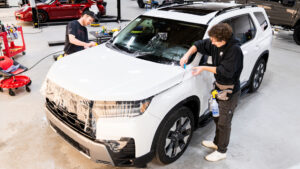 White SUV receiving full hood paint protection film (PPF) installation for enhanced front-end protection.