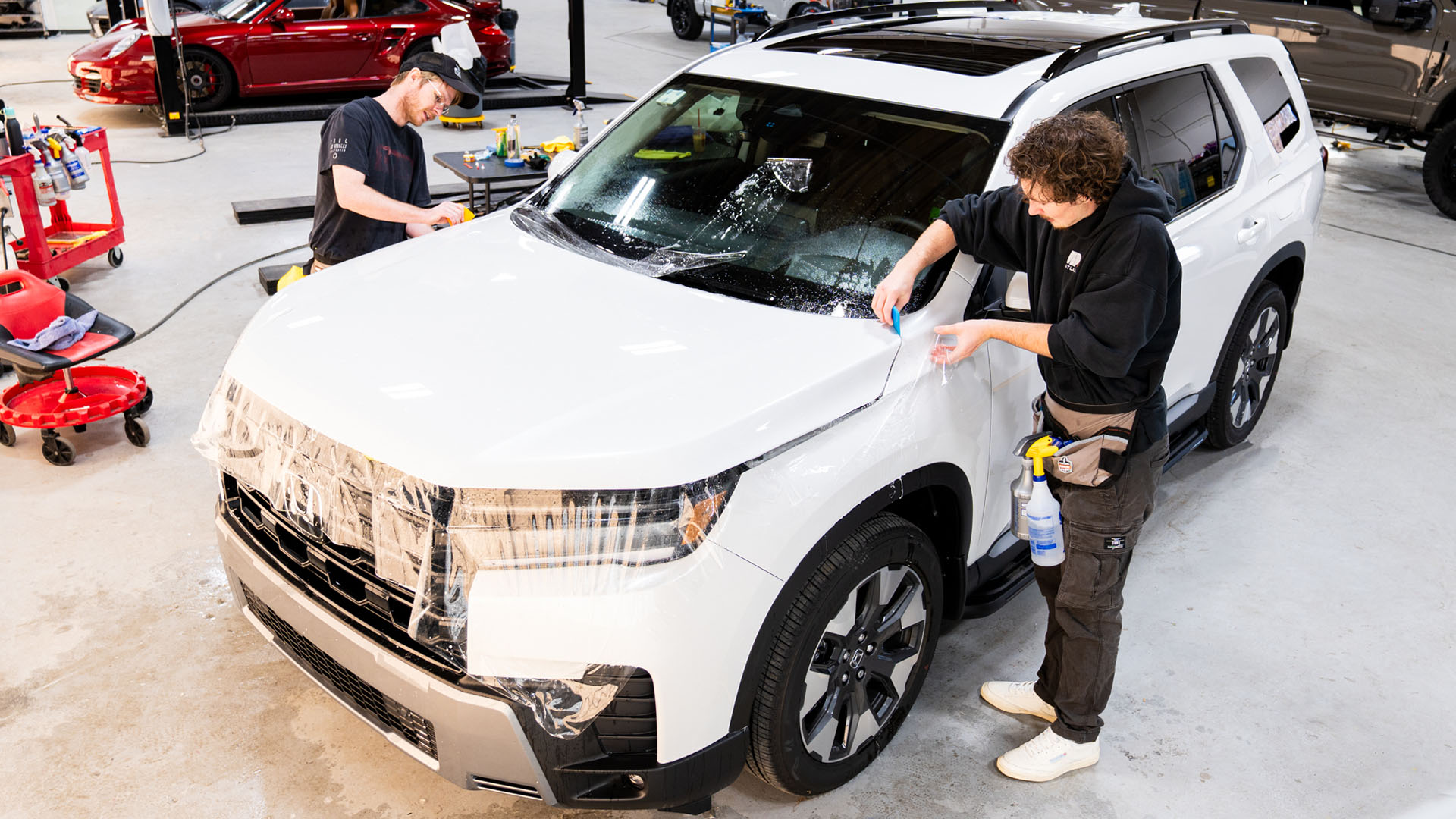 White SUV receiving full hood paint protection film (PPF) installation for enhanced front-end protection.